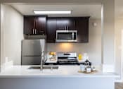 Thumbnail 27 of 31 - A modern kitchen with dark brown cabinets and stainless steel appliances.