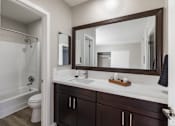 Thumbnail 31 of 31 - A bathroom with a white sink and a brown mirror.