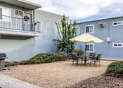 Thumbnail 33 of 40 - A patio with a table and chairs and a yellow umbrella.