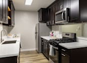 Thumbnail 40 of 40 - A kitchen with black cabinets and a white countertop.