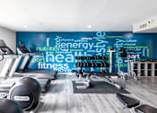 Thumbnail 19 of 31 - A gym with a variety of equipment and a wall with words related to fitness.