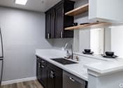 Thumbnail 1 of 31 - A modern kitchen with black cabinets and white countertops.