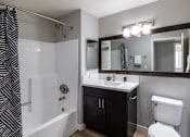 Thumbnail 9 of 31 - A bathroom with a black and white striped shower curtain.