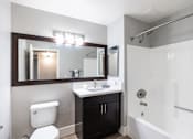 Thumbnail 31 of 31 - A bathroom with a toilet, sink, mirror, and bathtub.