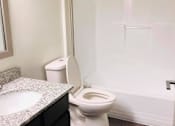 Thumbnail 8 of 16 - A white toilet sits next to a sink in a bathroom.