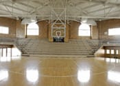 Thumbnail 7 of 16 - A basketball court with a wooden floor and a basketball hoop.