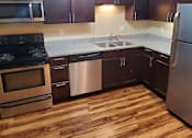Thumbnail 10 of 16 - A kitchen with dark brown cabinets and wooden floors.