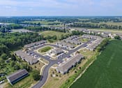 Thumbnail 19 of 23 - An aerial view of a large, open parking lot surrounded by buildings and green fields.