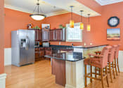 Thumbnail 17 of 23 - A kitchen with a black counter top and wooden cabinets.