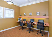 Thumbnail 18 of 23 - A room with four chairs and a desk with a laptop and a monitor.