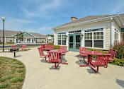 Thumbnail 20 of 23 - A red table and chairs are set up outside a building.