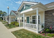 Thumbnail 11 of 23 - A white house with a porch and a green roof.