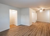 Thumbnail 4 of 9 - A room with wooden floors and white walls.