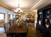 Thumbnail 11 of 18 - A dining room with a long table set for a meal.