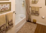 Thumbnail 16 of 18 - A bathroom with a tub, towel rack, and a rug.