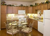 Thumbnail 12 of 18 - A kitchen with a table set for two and a white refrigerator.