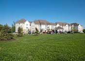 Thumbnail 1 of 18 - A large white building with a green lawn in front.