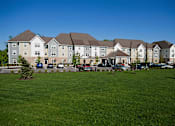 Thumbnail 2 of 18 - A large building with a parking lot in front of it.