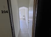 Thumbnail 6 of 23 - A hallway with a door at the end and a number 204 on the wall.