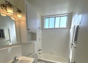 Thumbnail 16 of 21 - A white bathroom with a sink, toilet, and bathtub.