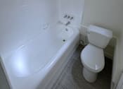 Thumbnail 22 of 23 - A white toilet sits next to a bathtub in a bathroom.
