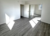 Thumbnail 10 of 21 - A room with wooden flooring and white walls.