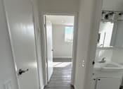 Thumbnail 15 of 21 - A long white hallway with a bathroom at the end.