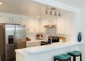 Thumbnail 2 of 12 - White kitchen cabinets and white counter tops featuring stainless steel appliances