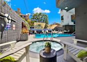 Thumbnail 2 of 34 - A hot tub sits in the middle of a patio with a white bench and a black table at Westwood Riviera Apartments, Los Angeles, 90024