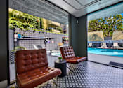Thumbnail 18 of 34 - Two brown leather chairs are placed in front of a glass wall at Westwood Riviera Apartments, Los Angeles