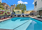 Thumbnail 4 of 34 - A swimming pool with a yellow umbrella and a white chair. at Westwood Riviera Apartments, Los Angeles