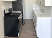 Thumbnail 8 of 21 - A black stove and refrigerator in a kitchen with white cabinets.