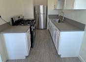 Thumbnail 11 of 23 - A kitchen with white cabinets and a stainless steel refrigerator.
