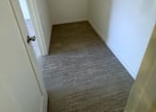 Thumbnail 19 of 23 - A hallway with a door on the left and a light switch on the wall.