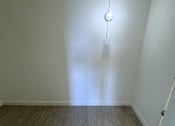 Thumbnail 18 of 23 - A white wall with a light bulb hanging from it.