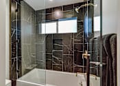 Thumbnail 10 of 18 - a bathroom with black tile and a shower and a tub at 8535 Colgate-Fully Furnished Apartments, Los Angeles, California