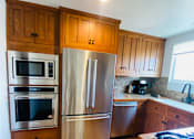 Thumbnail 14 of 18 - a kitchen with stainless steel appliances and wooden cabinets at 8535 Colgate-Fully Furnished Apartments, Los Angeles, CA