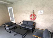 Thumbnail 21 of 21 - A living room with black furniture and a life preserver on the wall.