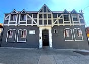 Thumbnail 1 of 23 - A building with a black and white facade has a black door and windows.