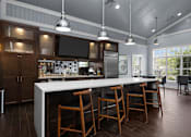 Thumbnail 17 of 18 - A kitchen with a white island and wooden chairs. at Merion at Cross Keys Apartments, Williamstown, 08094