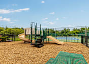 Thumbnail 8 of 21 - A playground with a slide and a green mat.