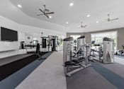 Thumbnail 4 of 21 - A spacious gym with a variety of equipment and a flat screen TV mounted on the wall.