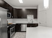 Thumbnail 12 of 15 - A kitchen with black cabinets and a white countertop.