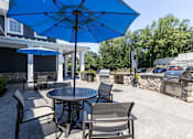 Thumbnail 3 of 19 - A blue umbrella is over a table with chairs.