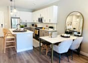 Thumbnail 4 of 20 - A modern kitchen with a dining table and chairs.