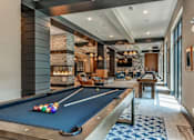 Thumbnail 9 of 20 - A pool table is in the middle of a room with a fireplace and a couch.