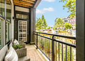 Thumbnail 18 of 23 - A balcony with a chair and a table with a potted plant on it.