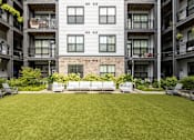 Thumbnail 3 of 23 - A large grassy area in front of a building with balconies.