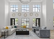 Thumbnail 8 of 23 - A modern living room with a grey sofa, a white couch, a coffee table, and a chandelier.