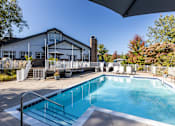 Thumbnail 27 of 27 - A swimming pool is surrounded by a white fence and a building.